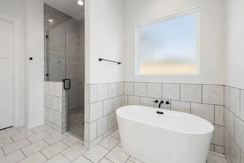 a white bath tub sitting in a bathroom and mirror