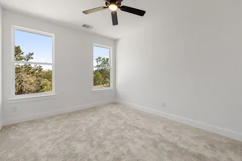 an empty room with windows and fan