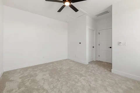an empty room with a ceiling fan and carpet