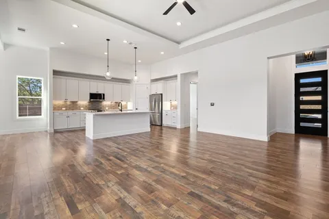a view of a kitchen with a sink and dishwasher a refrigerator with wooden floor