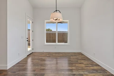 a large white kitchen with wooden floors and stainless steel appliances