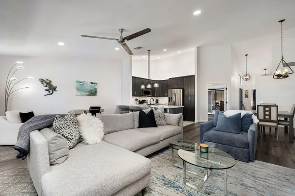 a living room with furniture kitchen view and a wooden floor