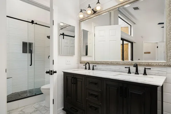 a bathroom with a double vanity sink mirror and shower