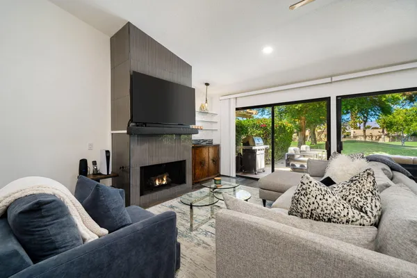 a living room with furniture fireplace and large windows