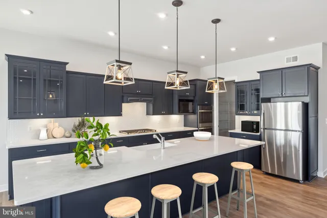 a kitchen with stainless steel appliances a dining table chairs and white cabinets
