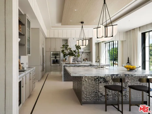 a large white kitchen with kitchen island granite countertop a large counter and chairs