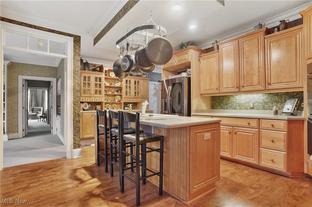 5612 Ridge Road Wadsworth, OH 44281 - Photo 10 of 33 Kitchen featuring a kitchen island, a kitchen breakfast bar, ornamental molding, stainless steel fridge with ice dispenser, and light brown cabinets