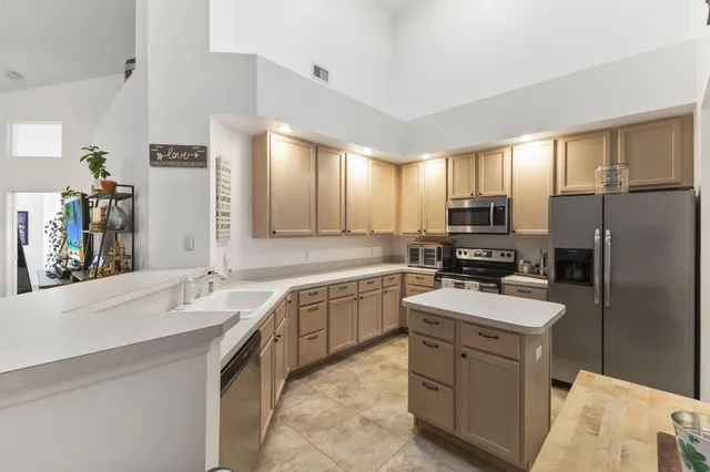a large kitchen with a sink stainless steel appliances and counter space