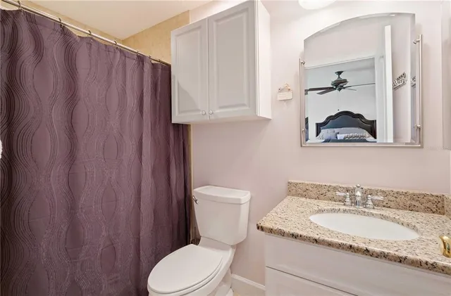 a bathroom with a granite countertop toilet and a sink