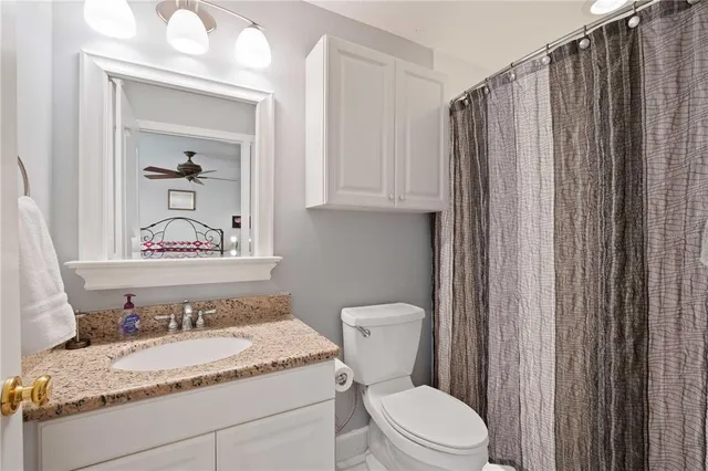 a bathroom with a granite countertop sink and a mirror with toilet