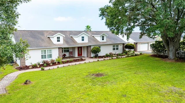 a view of an house with table and chairs under an umbrella