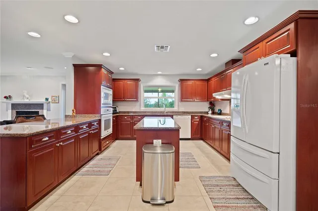 a kitchen with stainless steel appliances kitchen island granite countertop a stove a sink dishwasher and a refrigerator with wooden floor