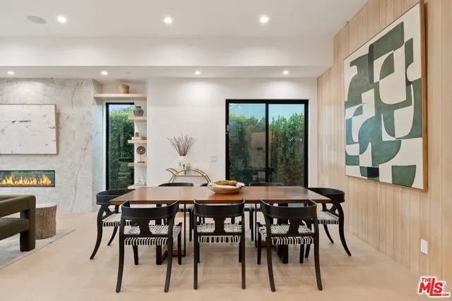 a kitchen with stainless steel appliances granite countertop a stove a refrigerator a sink a dining table and chairs