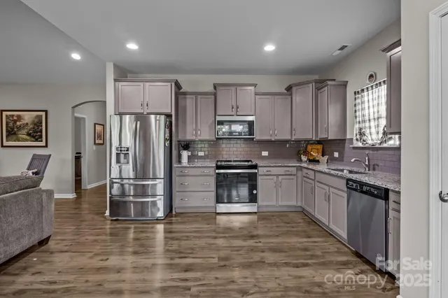 a kitchen with stainless steel appliances granite countertop a refrigerator sink and stove