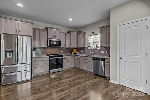 a kitchen with granite countertop a refrigerator and a stove top oven