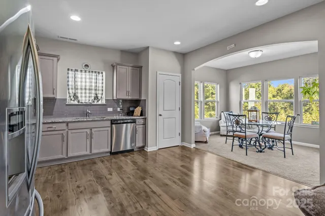 a kitchen with granite countertop a refrigerator stove dining table and chairs