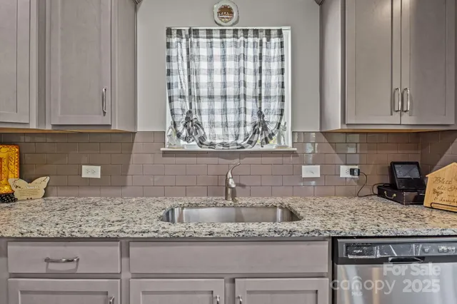 a kitchen with granite countertop a sink window and cabinets