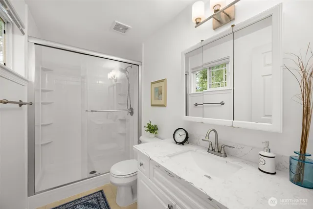 a bathroom with a granite countertop sink a toilet and shower