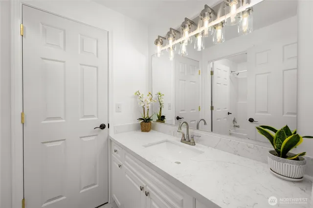 a bathroom with a sink a potted plant and a mirror