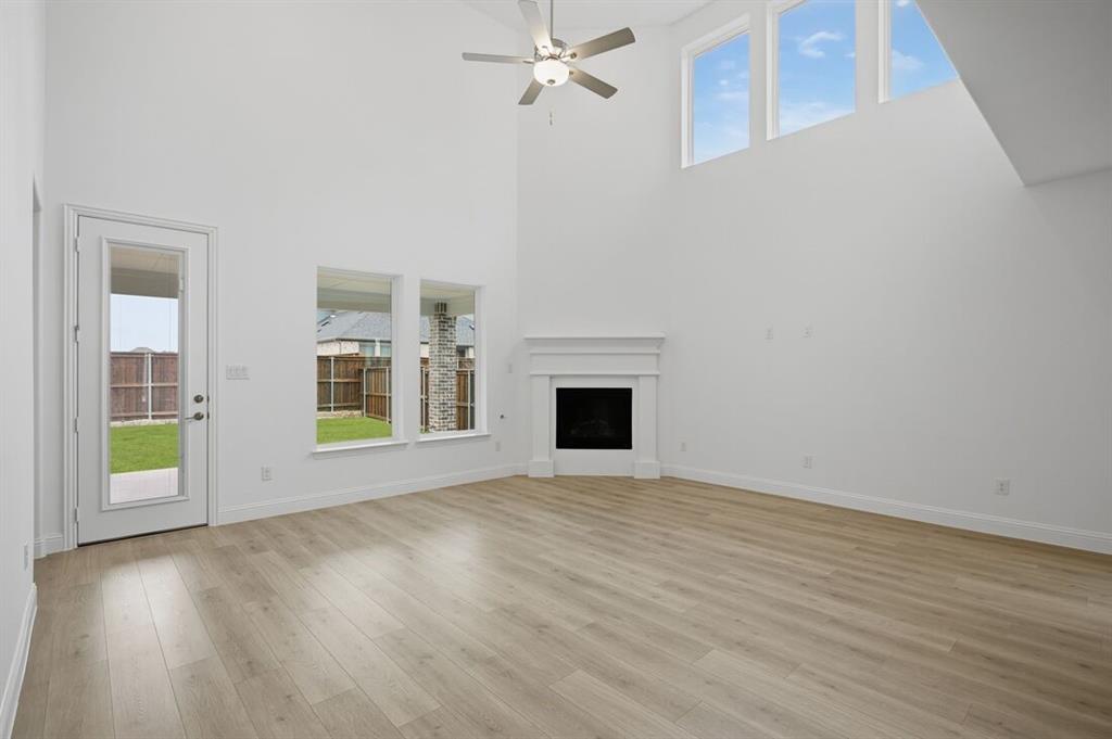 1604 Victory Circle Justin, TX 76247 - Photo 7 of 40 wooden floor fireplace and windows in an empty room