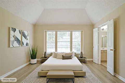 a spacious bedroom with a bed a window and a rug