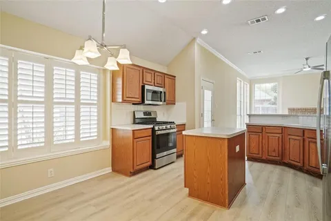 a open kitchen with stainless steel appliances granite countertop a stove top oven a sink dishwasher a dining table and chairs with wooden floor