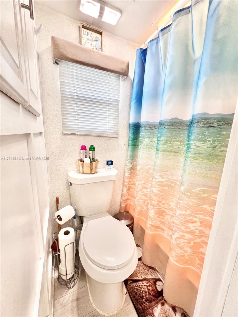 325 Calusa Street, Unit 5 Key Largo, FL 33037 - Photo 5 of 21 a bathroom with a toilet and a shower curtain