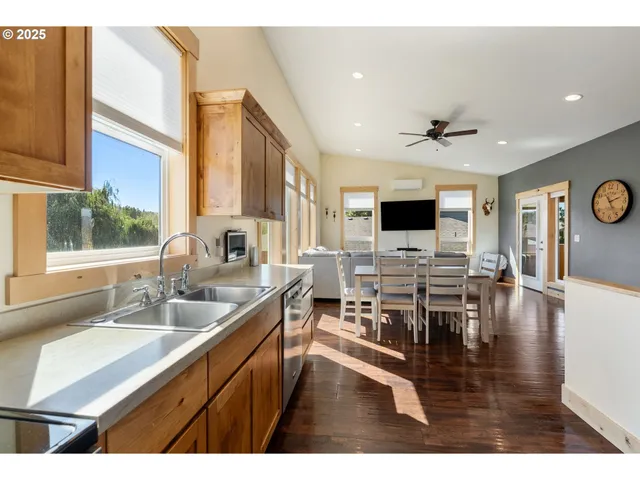 a living room with stainless steel appliances kitchen island granite countertop a sink a stove and a microwave oven with wooden floor