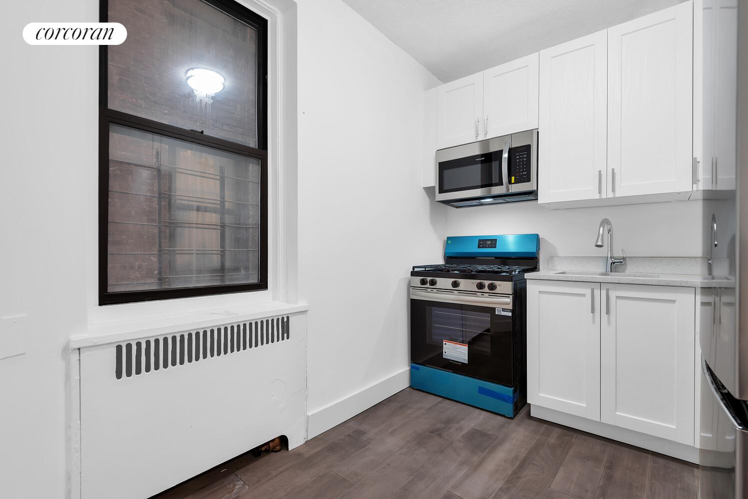 3245 Perry Avenue, Unit 1B Bronx, NY 10467 - Photo 3 of 6 a kitchen with stainless steel appliances granite countertop a stove a microwave and a refrigerator