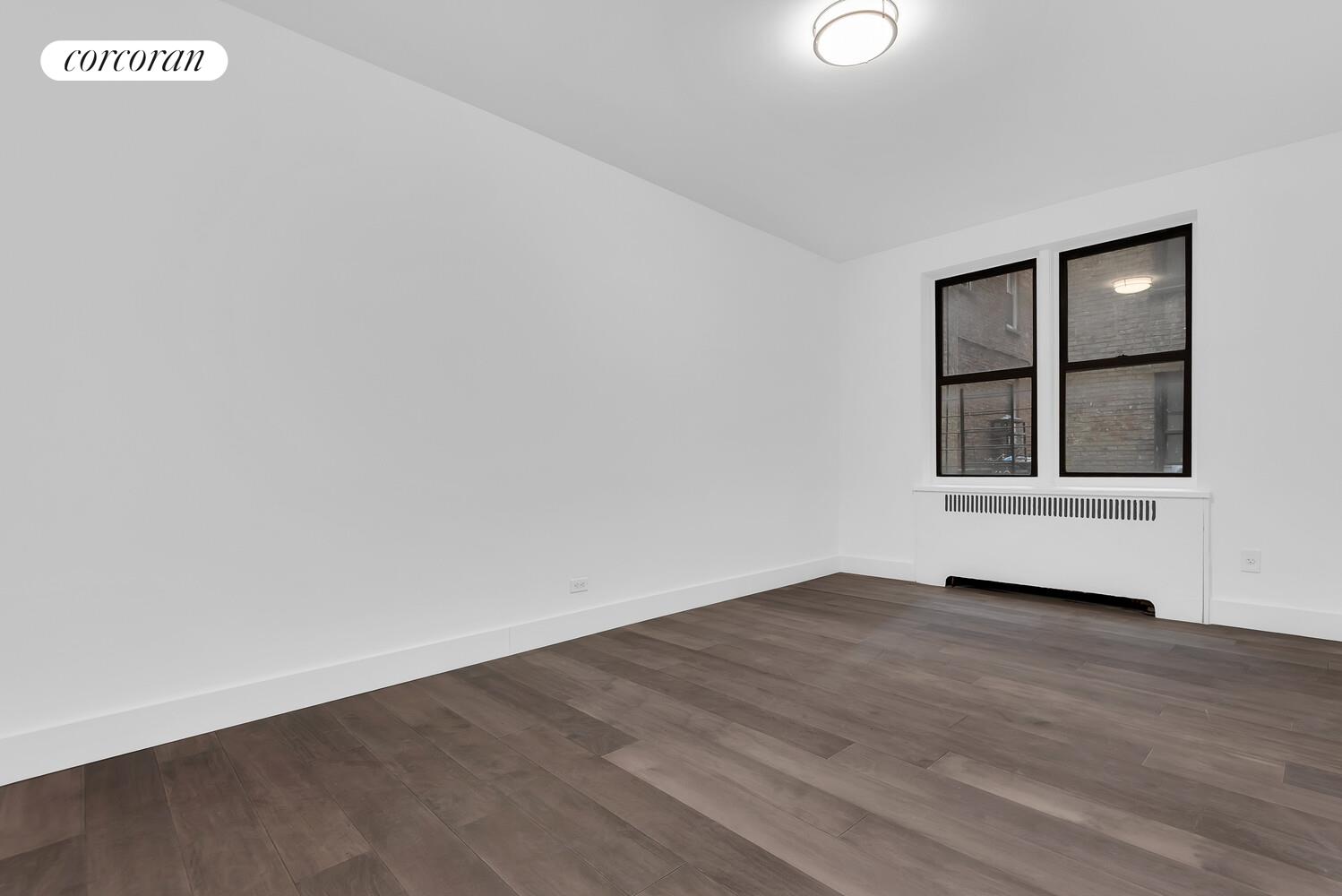 3245 Perry Avenue, Unit 1B Bronx, NY 10467 - Photo 4 of 6 a view of an empty room with wooden floor and windows