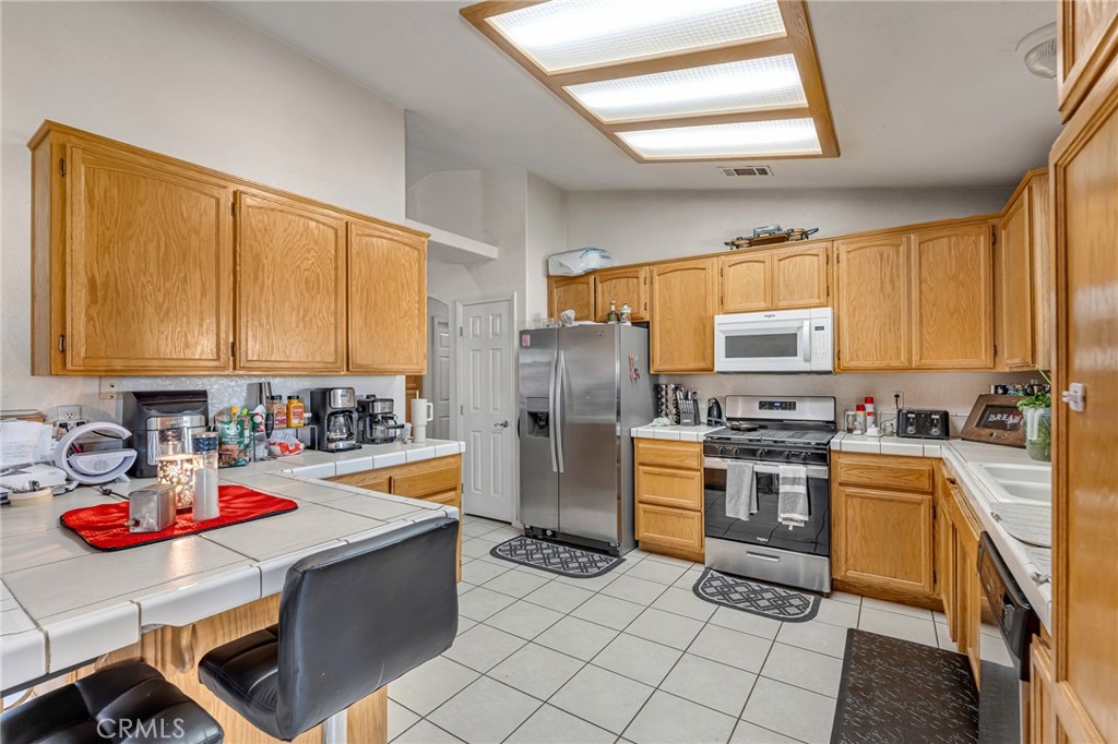 19084 Rock Springs Road Hesperia, CA 92345 - Photo 12 of 44 a kitchen with stainless steel appliances kitchen island granite countertop a sink dishwasher stove and refrigerator
