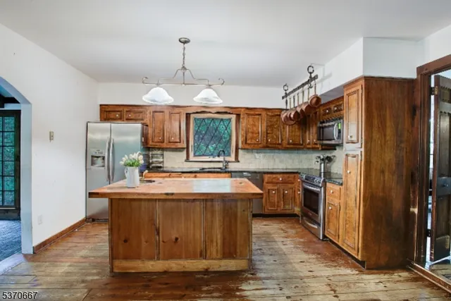 a large kitchen with kitchen island a stove a refrigerator a sink dishwasher and wooden cabinets with wooden floor