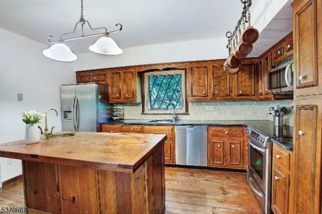 a kitchen with stainless steel appliances granite countertop a sink and a refrigerator