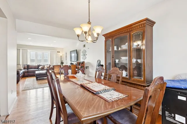 a view of a dining room and livingroom with furniture wooden floor a rug a potted plant and a chandelier