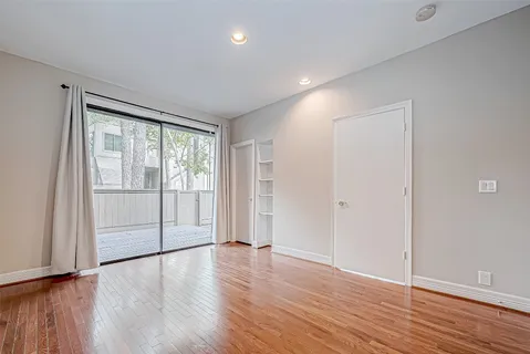 a view of an empty room with wooden floor and a kitchen