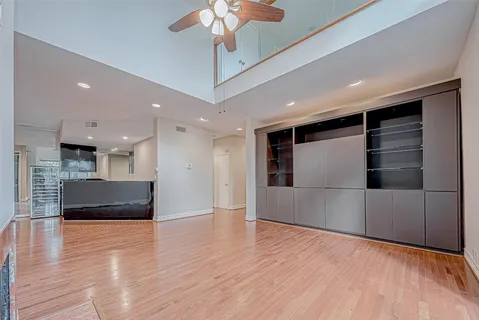 a view of an empty room with wooden floor and a kitchen