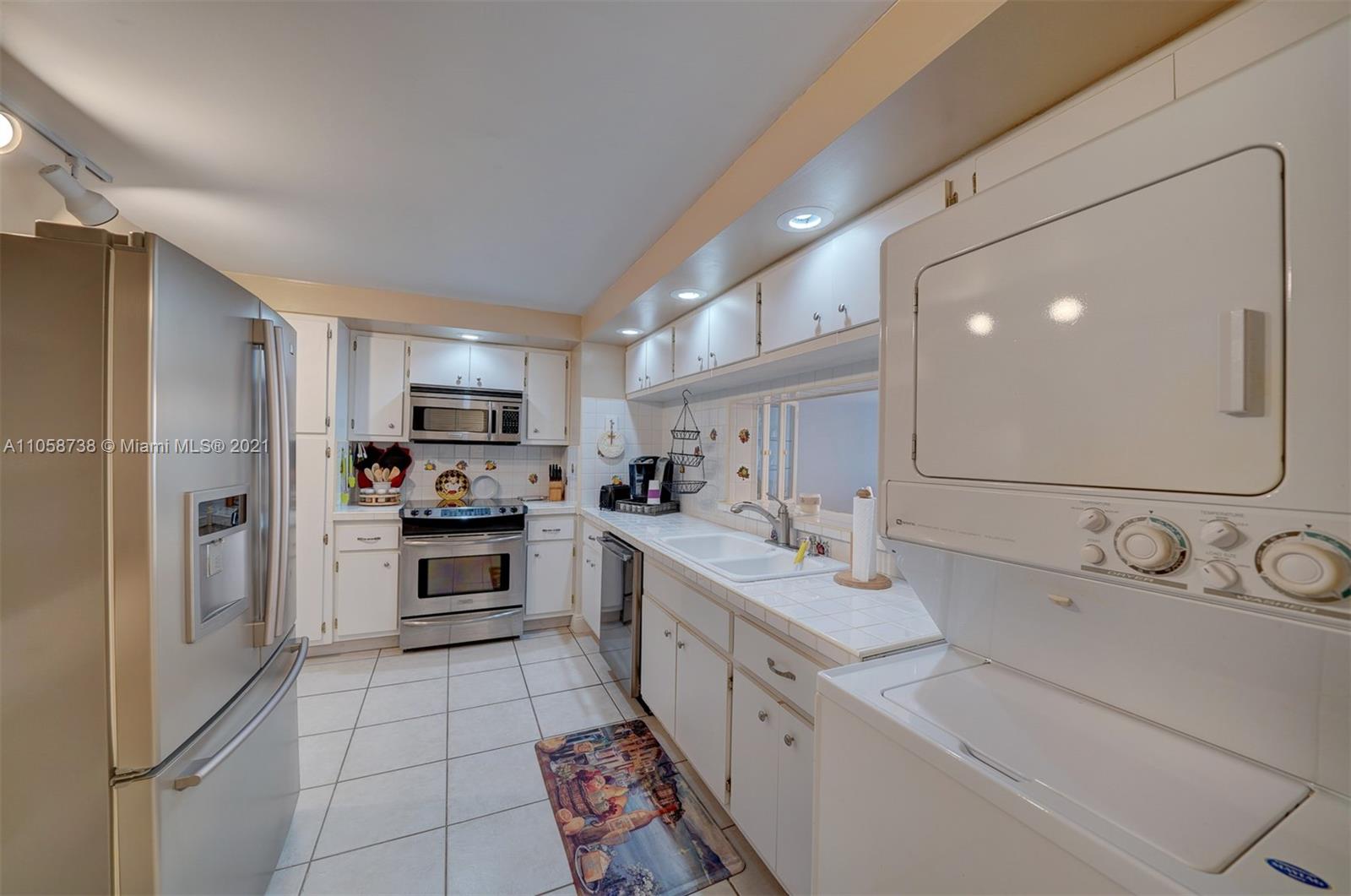 a large kitchen with a sink stainless steel appliances and cabinets