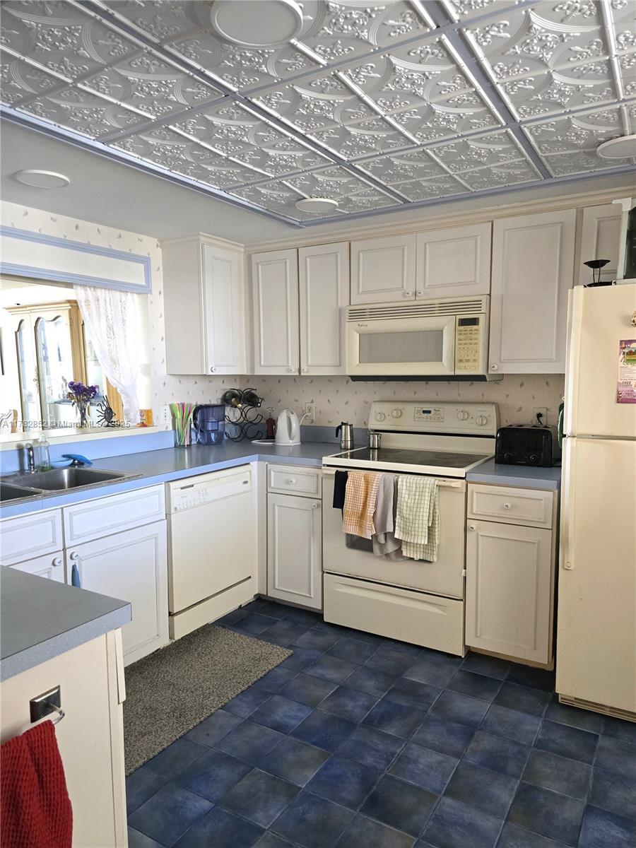 7020 Half Moon Circle, Unit 511 Hypoluxo, FL 33462 - Photo 11 of 28 a kitchen with white cabinets and white appliances