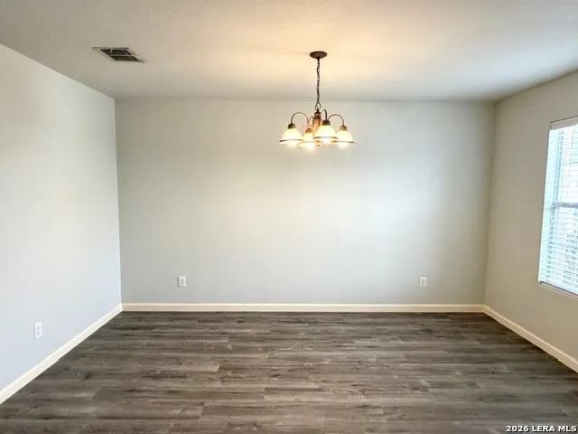 a view of empty room with window and chandelier