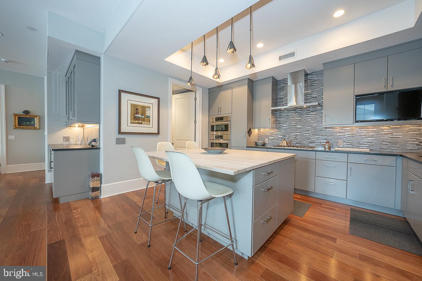100 St Georges Road, Unit A3 Ardmore, PA 19003 - Photo 14 of 43 a kitchen with stainless steel appliances granite countertop a kitchen island hardwood floor sink stove dining table and chairs