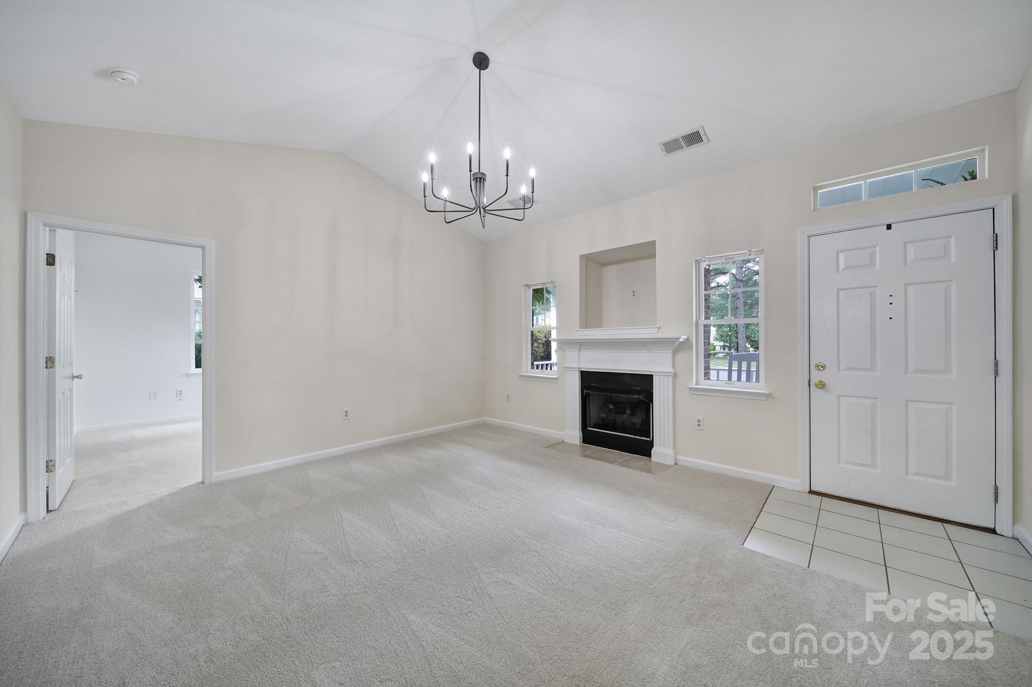 614 Stone Village Drive Fort Mill, SC 29708 - Photo 5 of 42 an empty room with fireplace chandelier and windows