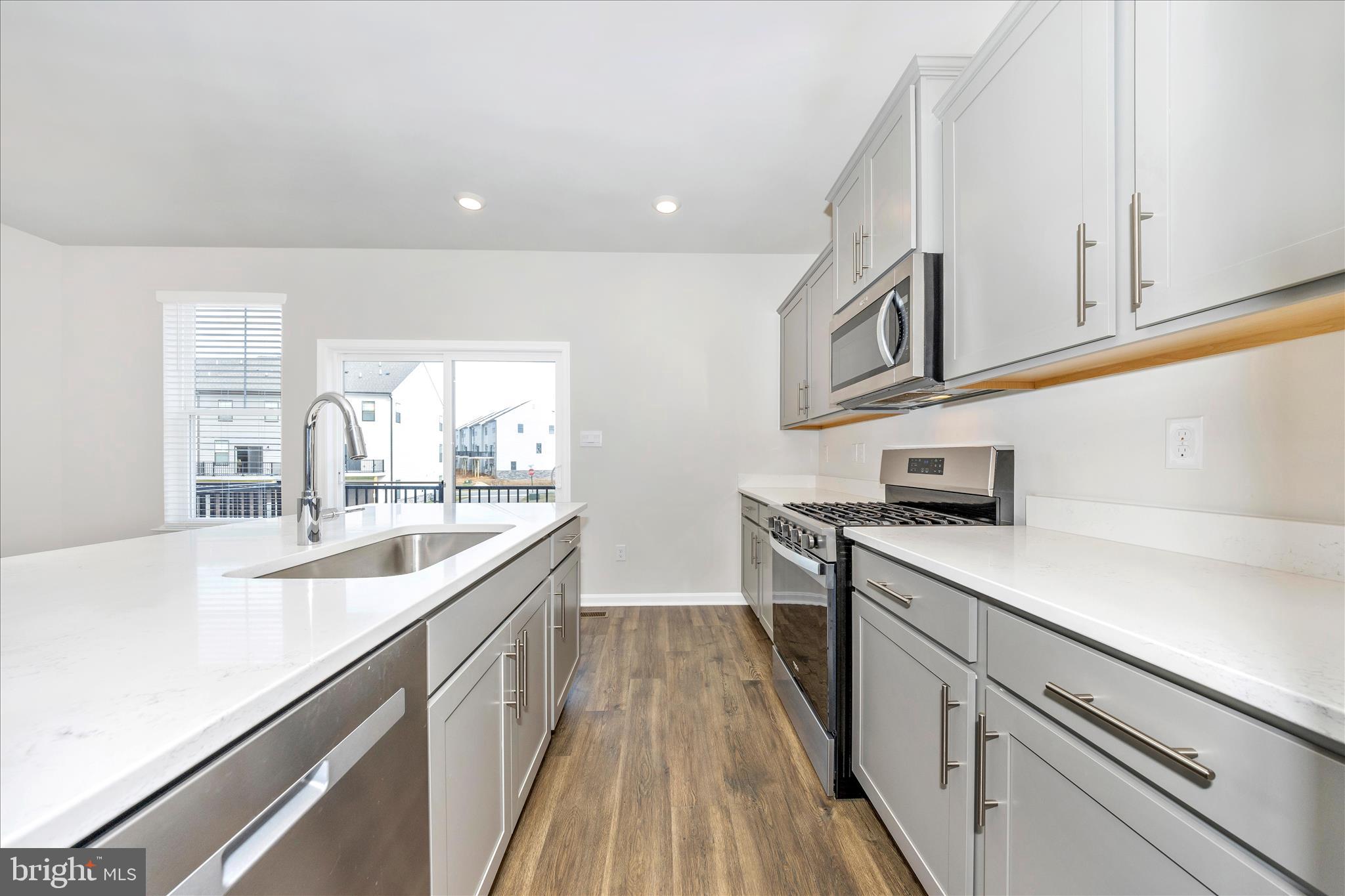 726 Compass Way Frederick, MD 21701 - Photo 20 of 55 a kitchen with stainless steel appliances granite countertop a sink and dishwasher a stove top oven with wooden floor
