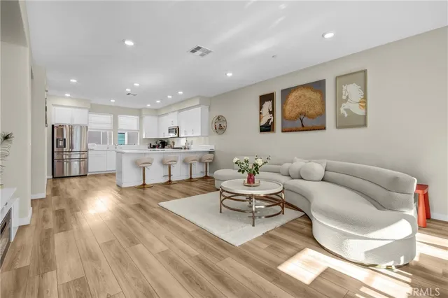 a living room with furniture and kitchen view with wooden floor