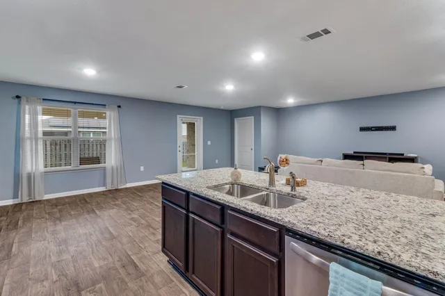 a kitchen with kitchen island granite countertop a sink cabinets and wooden floor
