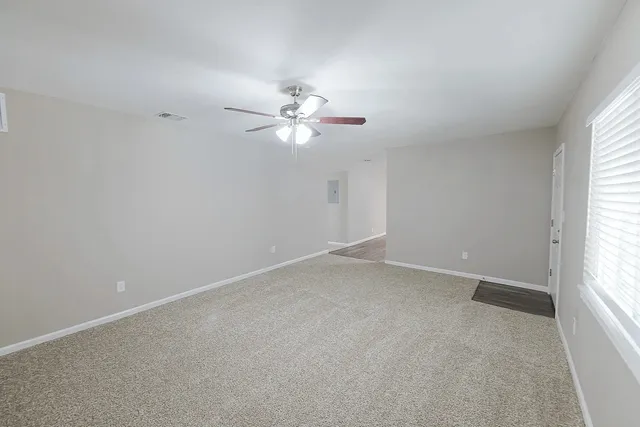 an empty room with a window and a ceiling fan