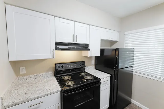 a kitchen with stainless steel appliances granite countertop white cabinets and a stove