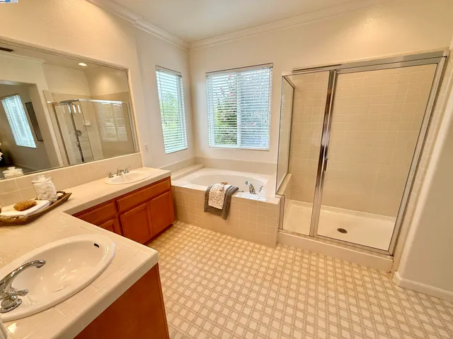 a bathroom with a sink double vanity granite tub shower and a mirror