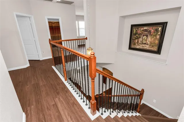 a view of a hallway with wooden floor and stairs