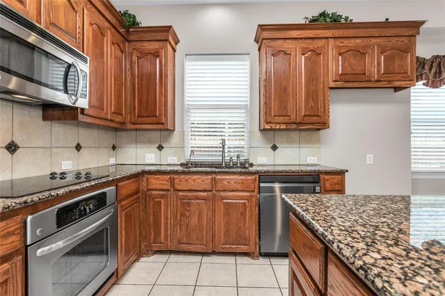 a kitchen with stainless steel appliances granite countertop a stove a sink a oven a dining table and chairs