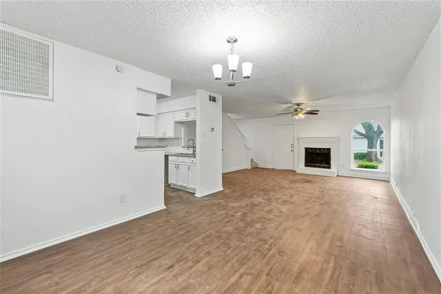 a view of a livingroom with a fireplace a chandelier and wooden floor
